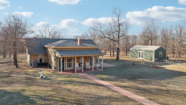 448 Springview Dr, Skiatook, OK 74070 - back of house featuring a lawn, an outdoor fire pit, roof with shingles, central air condition unit, and a chimney
