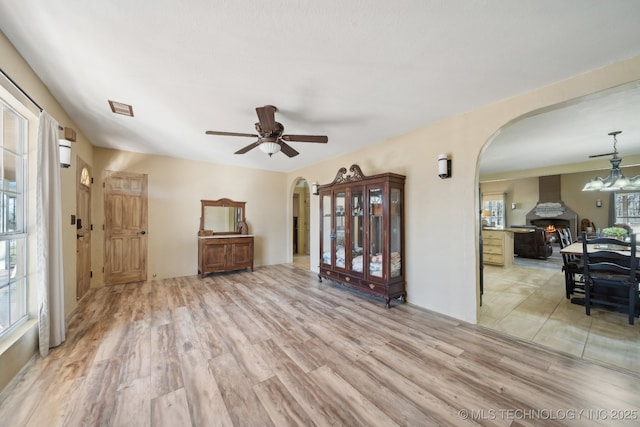 448 Springview Dr, Skiatook, OK 74070 - living room featuring arched walkways, light wood finished floors, a chandelier, and ceiling fan