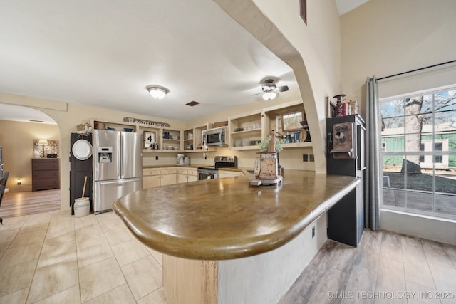 448 Springview Dr, Skiatook, OK 74070 - kitchen featuring appliances with stainless steel finishes, open shelves, arched walkways, a peninsula, and a ceiling fan