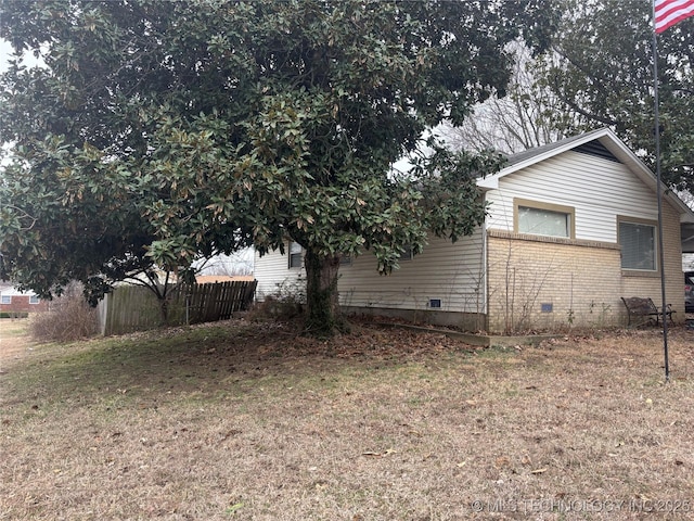 view of side of property with crawl space, fence, a lawn, and brick siding