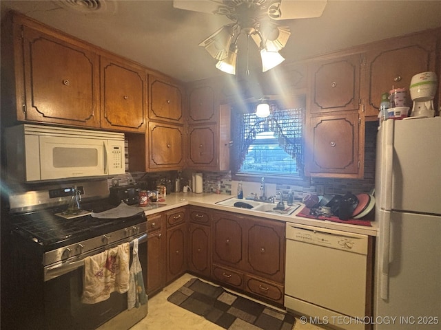 kitchen featuring white appliances, tasteful backsplash, light countertops, and a sink