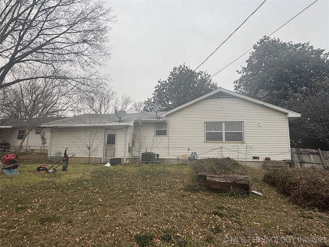 rear view of house with a yard, central AC unit, and fence