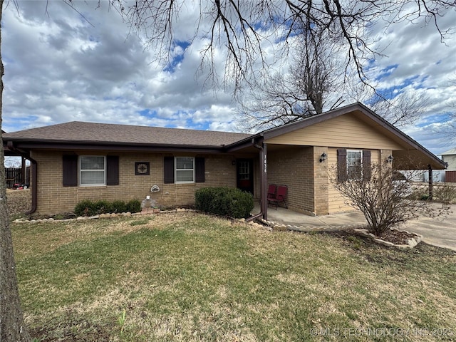 single story home featuring concrete driveway, a front lawn, a patio, and brick siding