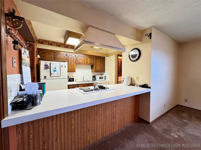 kitchen with custom exhaust hood, dark carpet, decorative backsplash, white appliances, and a peninsula