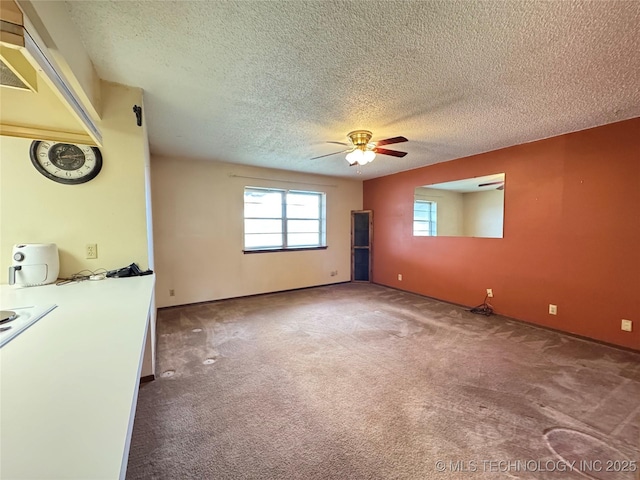 carpeted spare room featuring a textured ceiling and a ceiling fan