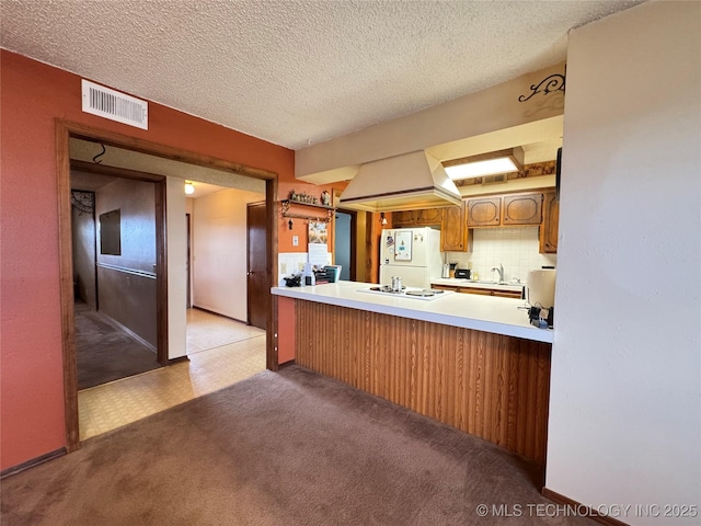 kitchen with visible vents, freestanding refrigerator, light countertops, a textured ceiling, and a sink