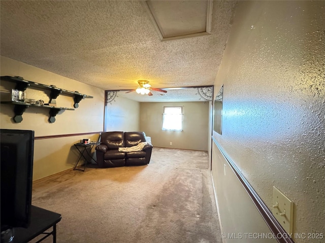 interior space with baseboards, a ceiling fan, a textured ceiling, and a textured wall