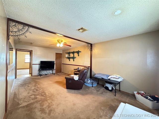 carpeted living room with a textured ceiling, visible vents, and a ceiling fan