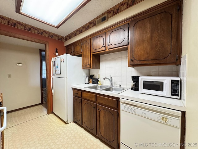 kitchen featuring white appliances, a sink, light countertops, light floors, and tasteful backsplash