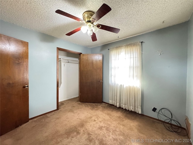 unfurnished bedroom with carpet floors, a textured ceiling, baseboards, and a closet