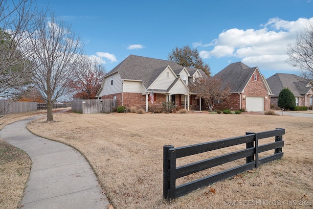 view of front of property with an attached garage, a fenced front yard, and brick siding