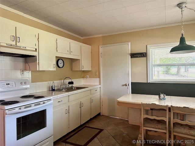 kitchen with under cabinet range hood, electric range, dark tile patterned floors, a sink, and crown molding