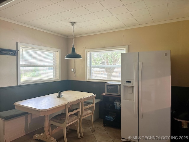 dining area with a healthy amount of sunlight, ornamental molding, breakfast area, and light tile patterned flooring