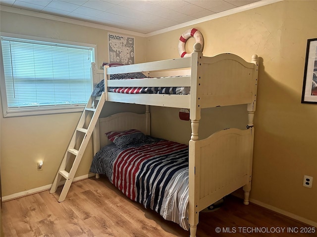 bedroom featuring baseboards, ornamental molding, and wood finished floors