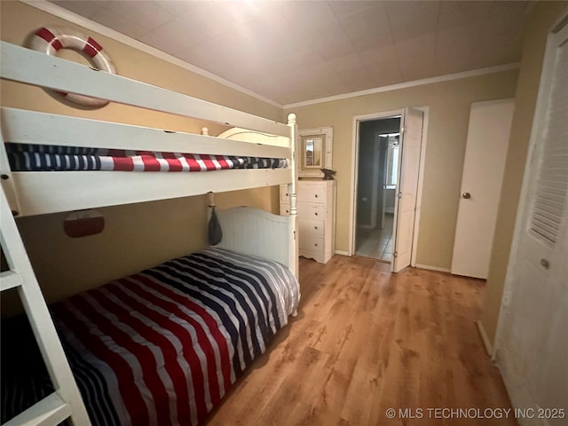 bedroom featuring ornamental molding, light wood-style floors, and baseboards