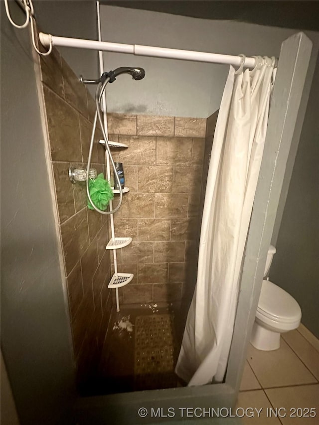 bathroom with toilet, a stall shower, and tile patterned flooring