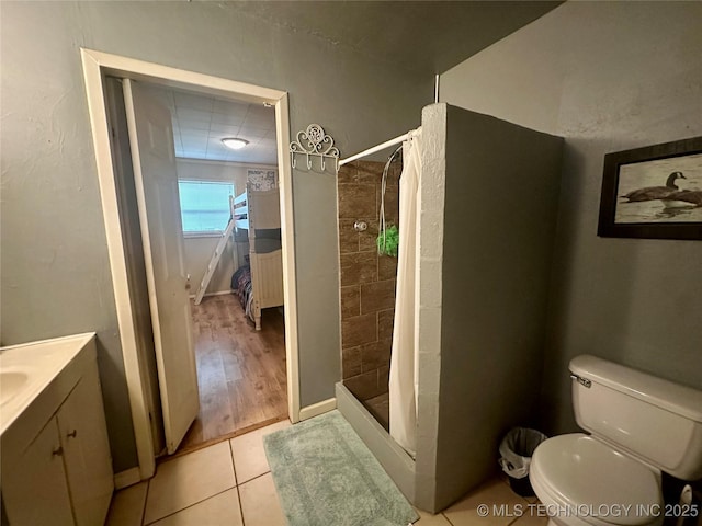 bathroom with baseboards, a shower stall, toilet, and tile patterned floors