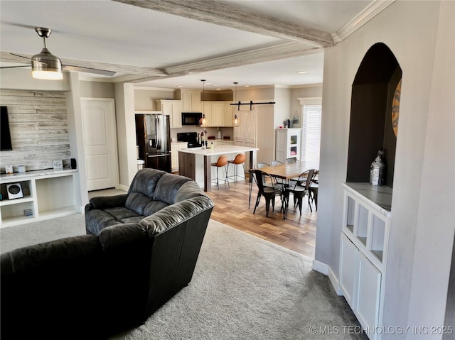 living area featuring a barn door, recessed lighting, baseboards, beam ceiling, and crown molding