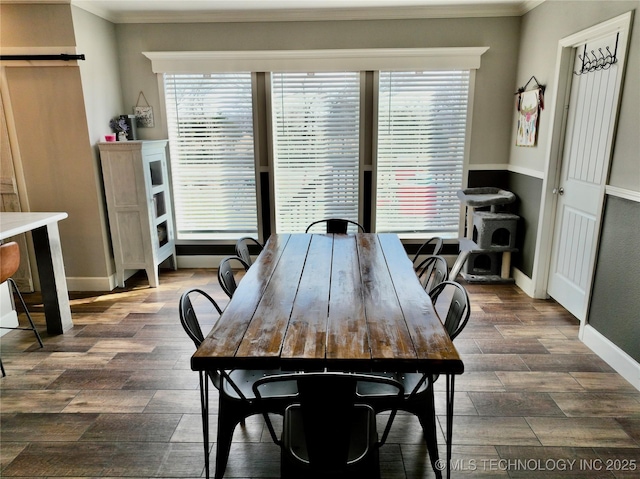 dining room featuring dark wood-style floors, ornamental molding, baseboards, and a barn door