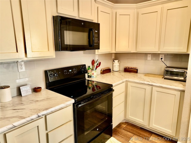 kitchen with light wood finished floors, black appliances, a toaster, and decorative backsplash