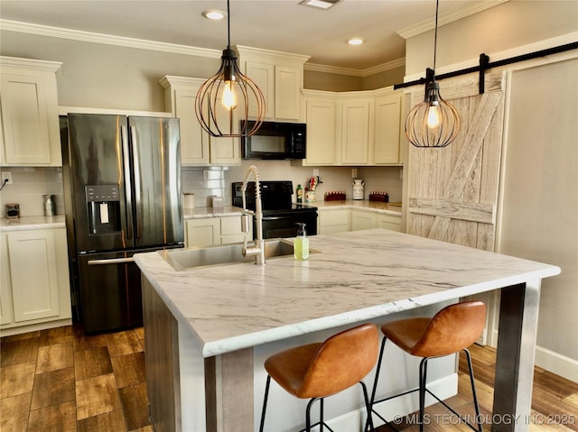 kitchen with ornamental molding, black appliances, a barn door, and dark wood-type flooring