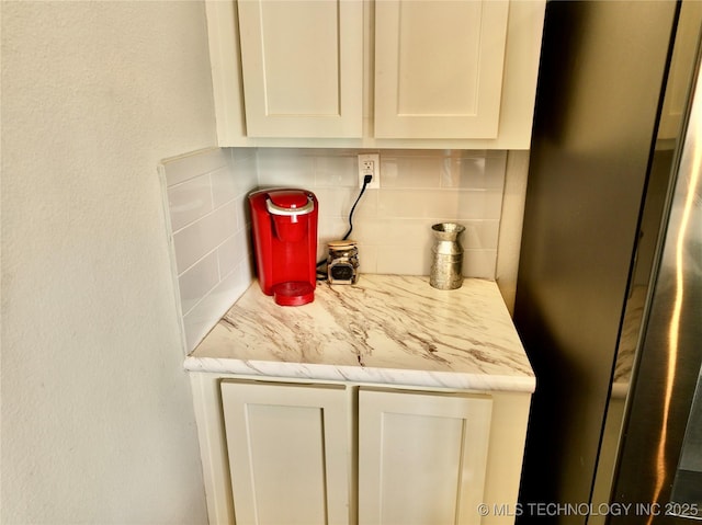 room details with freestanding refrigerator and decorative backsplash