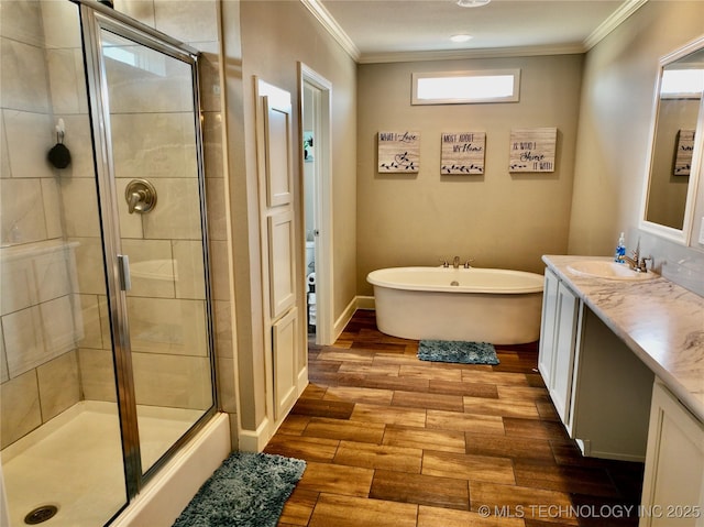 full bathroom with wood finish floors, a freestanding bath, ornamental molding, a stall shower, and vanity