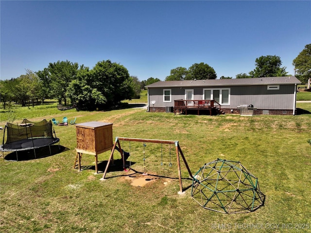 view of yard with a trampoline, a playground, and a deck