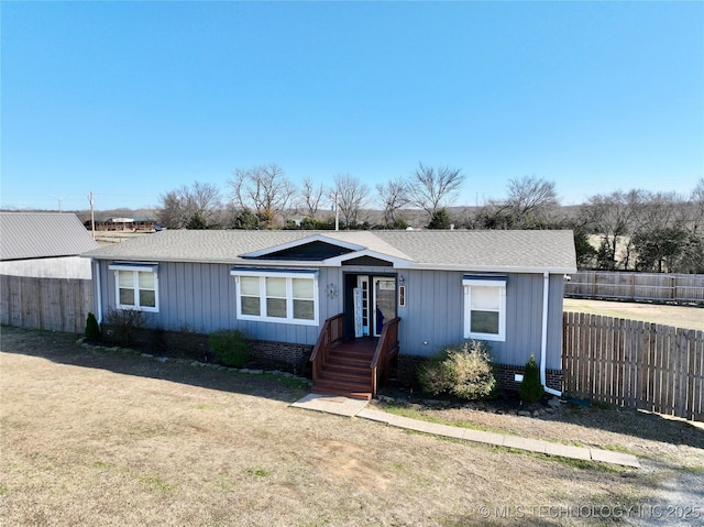 view of front of home featuring a front yard, fence, and a shingled roof