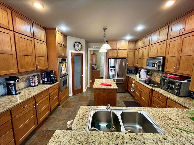 kitchen with tasteful backsplash, appliances with stainless steel finishes, brown cabinets, stone tile flooring, and a sink