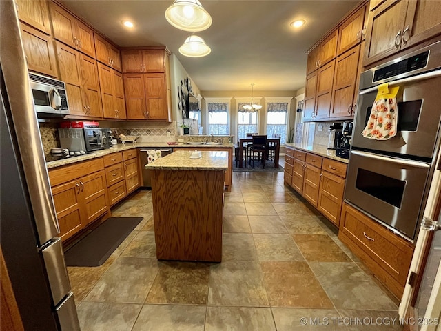 kitchen featuring stainless steel appliances, brown cabinetry, backsplash, and a center island