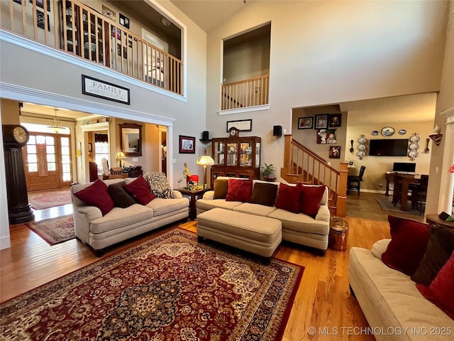 living room with ornate columns, a high ceiling, stairway, and wood finished floors