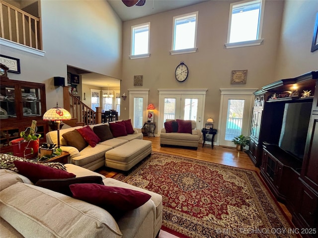 living room featuring ceiling fan with notable chandelier, stairway, and wood finished floors