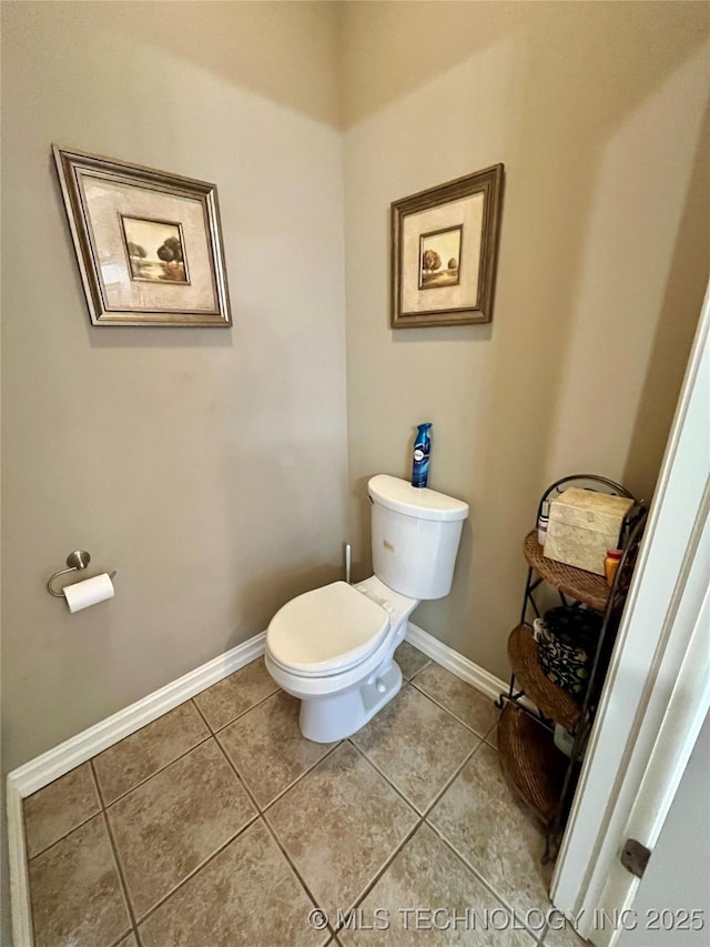 bathroom with tile patterned flooring, baseboards, and toilet