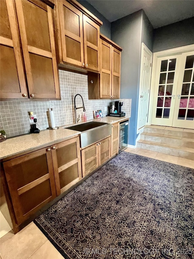 kitchen with wine cooler, french doors, light tile patterned floors, tasteful backsplash, and a sink