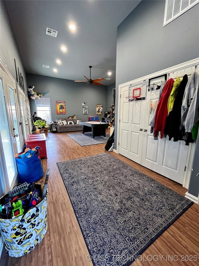 interior space with ceiling fan, wood finished floors, and visible vents