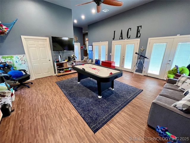 game room with visible vents, ceiling fan, wood finished floors, french doors, and high vaulted ceiling