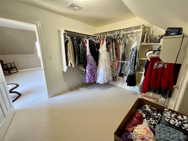 walk in closet with carpet, visible vents, and lofted ceiling