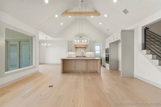 2719 E 135th Dr S, Bixby, OK 74008 - kitchen with light wood finished floors, a sink, backsplash, a chandelier, and beamed ceiling