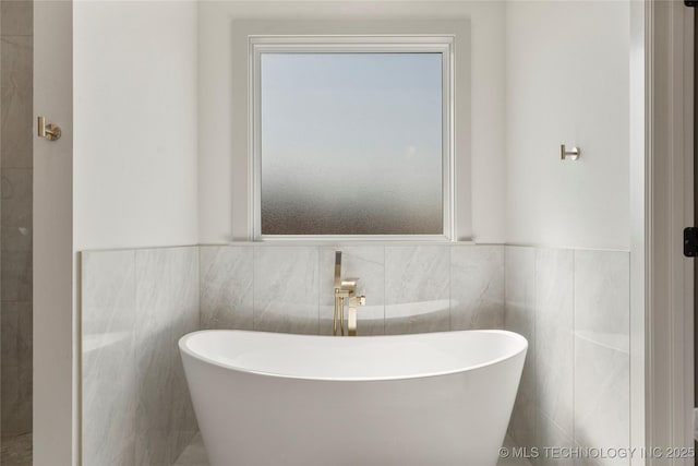 2719 E 135th Dr S, Bixby, OK 74008 - bathroom with tile walls, wainscoting, and a freestanding tub