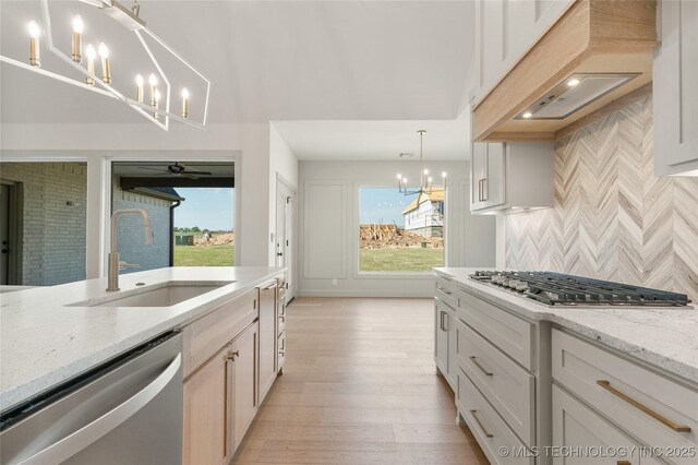 2719 E 135th Dr S, Bixby, OK 74008 - kitchen with light wood finished floors, a sink, appliances with stainless steel finishes, a notable chandelier, and custom range hood