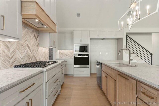 2719 E 135th Dr S, Bixby, OK 74008 - kitchen featuring light wood finished floors, visible vents, a sink, premium range hood, and appliances with stainless steel finishes