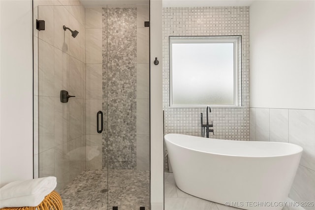 full bath with tile walls, a shower stall, and a soaking tub