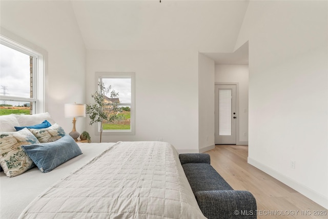 bedroom featuring high vaulted ceiling, wood finished floors, and multiple windows