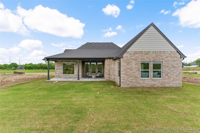 back of property featuring a lawn, a patio area, a shingled roof, and brick siding