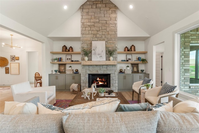 living room with high vaulted ceiling, wood finished floors, a stone fireplace, and built in features
