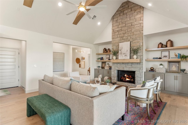 living room with recessed lighting, light wood-style flooring, ceiling fan, a stone fireplace, and high vaulted ceiling
