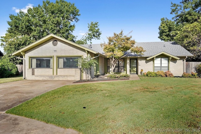 view of front of home with brick siding, fence, driveway, and a front lawn