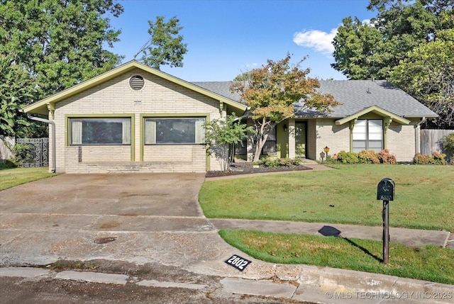 ranch-style home featuring brick siding, a shingled roof, concrete driveway, fence, and a front lawn