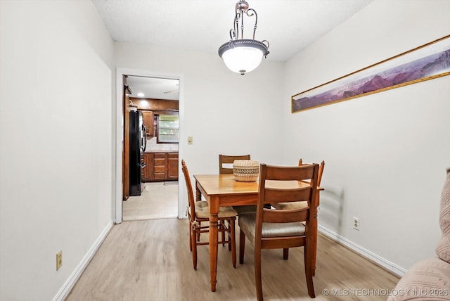 dining area with light wood-type flooring and baseboards